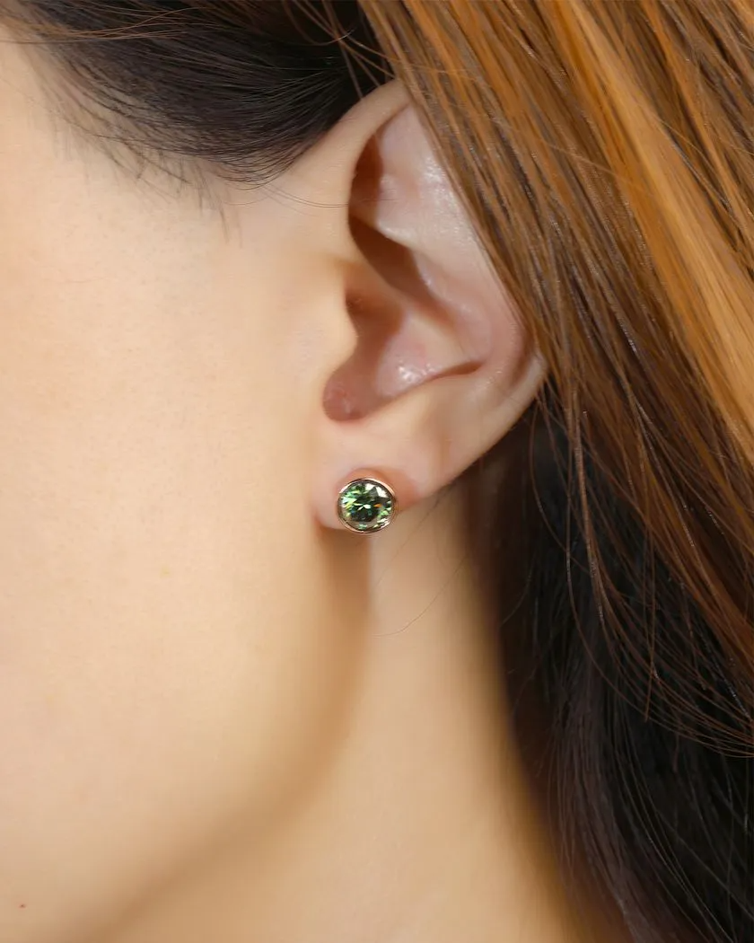 A model wearing a pair of elegant earrings, each featuring a one carat green moissanite stone set in a bezel rose gold setting.