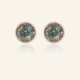 Modern and minimalistic one-carat gunmetal grey moissanite bezel studs set in rose gold, exuding understated elegance with a sleek metallic sparkle.