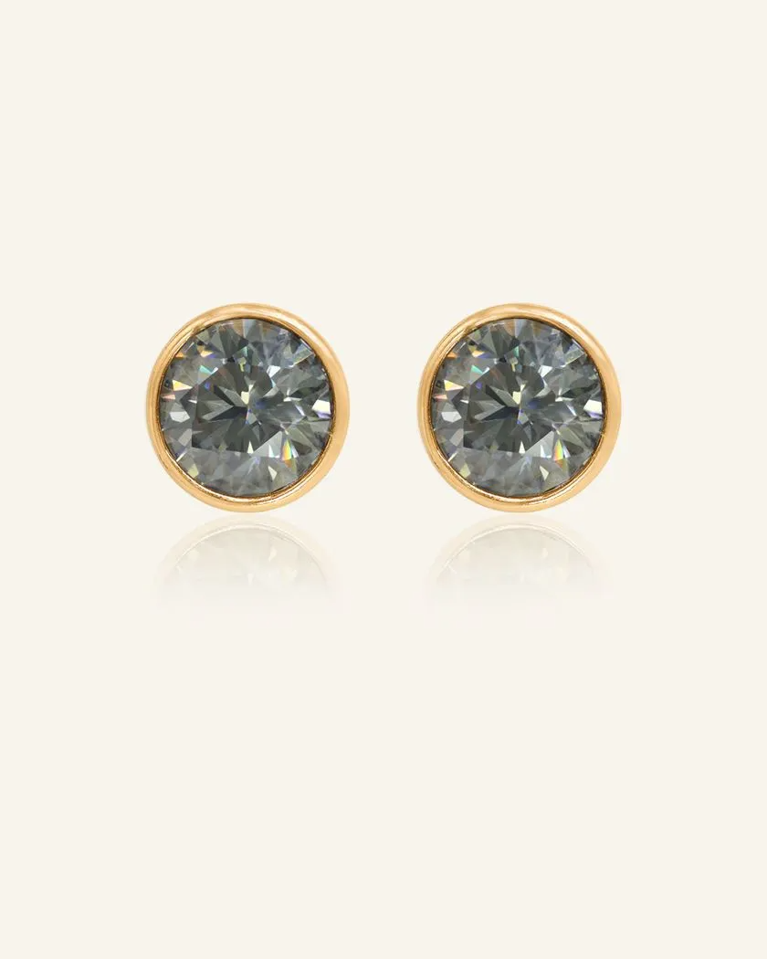 Modern and minimalistic one-carat gunmetal grey moissanite bezel studs set in yellow gold, exuding understated elegance with a sleek metallic sparkle.