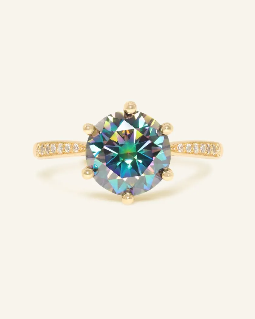 A stunning 3ct mystic moissanite ring featuring a large, vibrant, moissanite set in a yellow gold band.