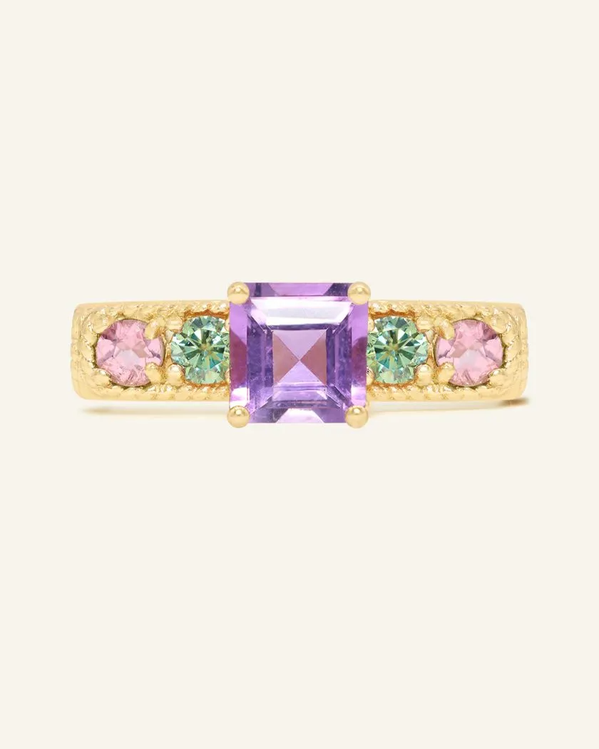 A yellow gold ring featuring a central square-cut amethyst stone, flanked by two pink tourmalines and two green moissanites on either side, set in a textured band,
