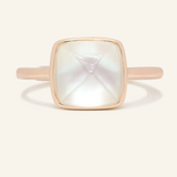 A rose gold ring featuring a large, faceted clear quartz stone cut in a sugarloaf shape, set in a simple, square bezel setting.