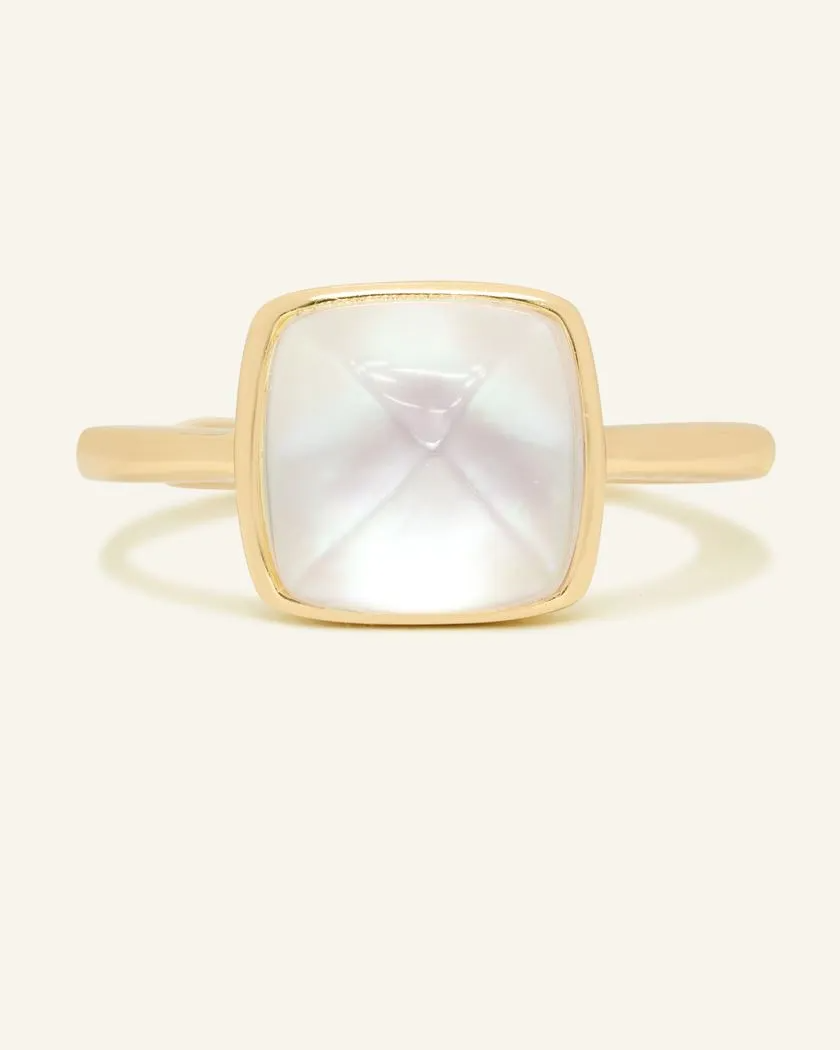 A yellow gold ring featuring a large, faceted clear quartz stone cut in a sugarloaf shape, set in a simple, square bezel setting.	