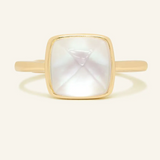 A yellow gold ring featuring a large, faceted clear quartz stone cut in a sugarloaf shape, set in a simple, square bezel setting.	