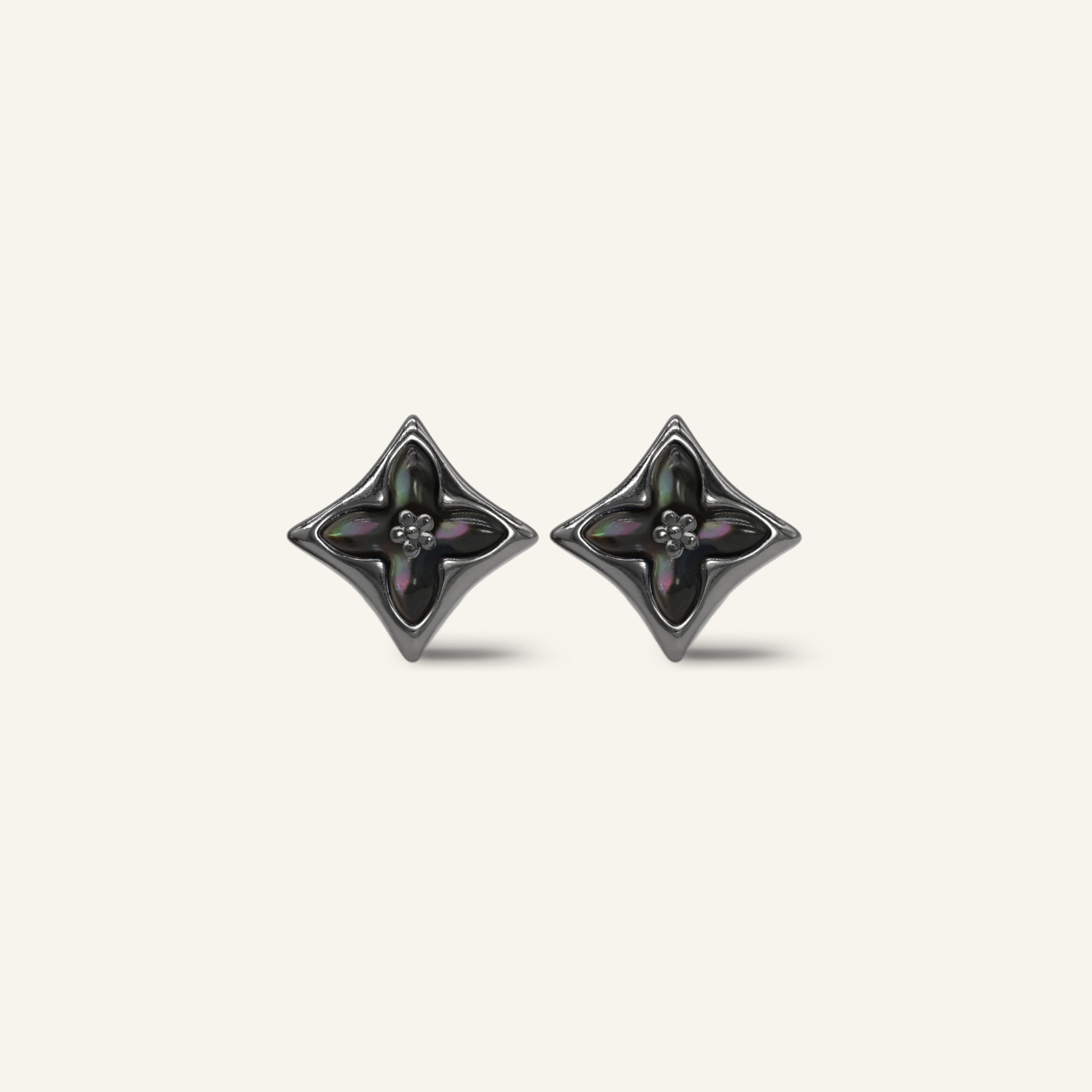 Close-up of a pair of black gold clover monogram studs