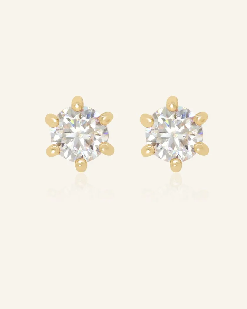 A pair of dainty white moissanite stud earrings set in yellow gold, featuring sparkling round-cut gemstones with a six-prong setting.	