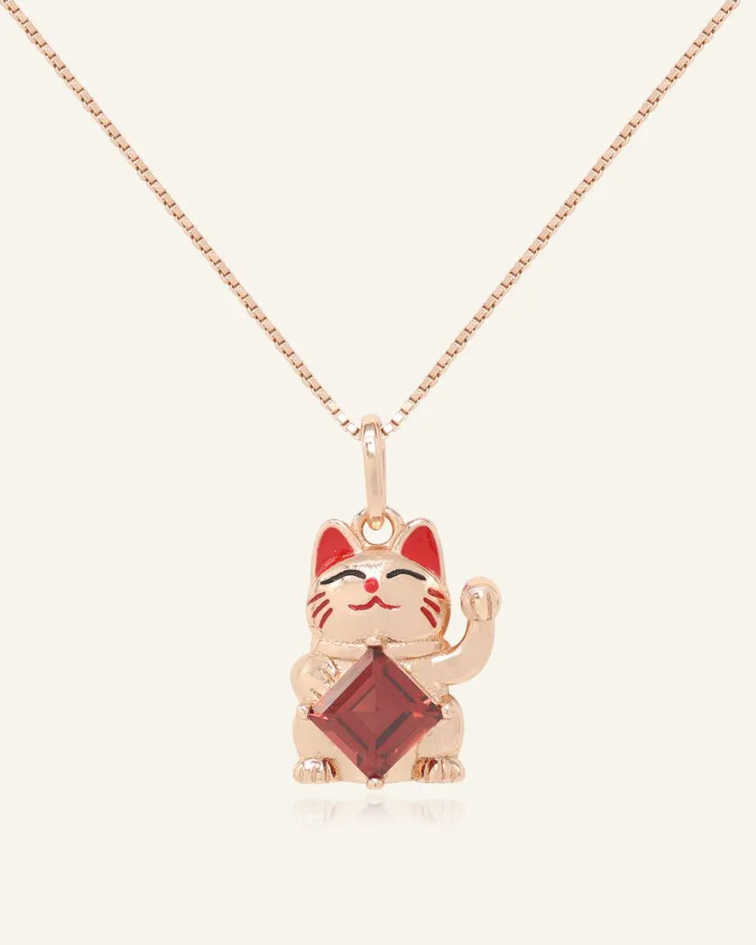 A charming fortune cat necklace featuring a playful cat motif in rose gold, holding a vibrant garnet gemstone, symbolizing luck, prosperity, and passion.