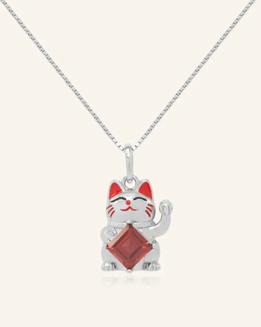 A charming fortune cat necklace featuring a playful cat motif in silver, holding a vibrant garnet gemstone, symbolizing luck, prosperity, and passion.