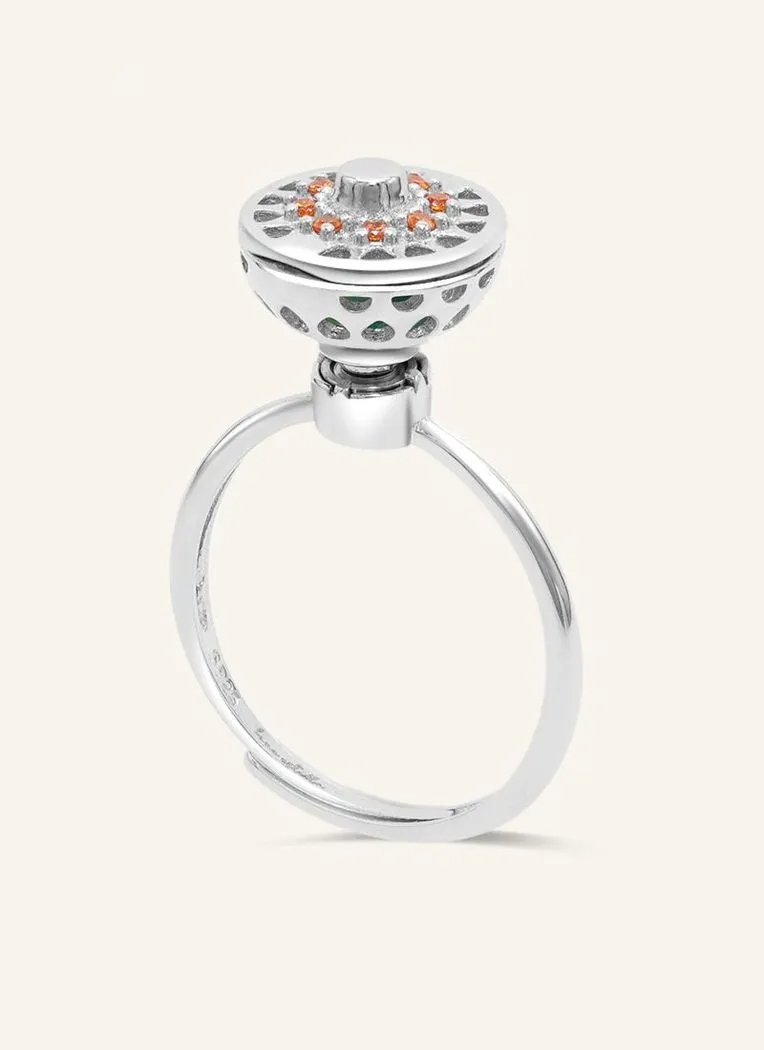 A silver ring with a rotating circular top that opens to reveal colorful gemstones inside, resembling a spinning hotpot.