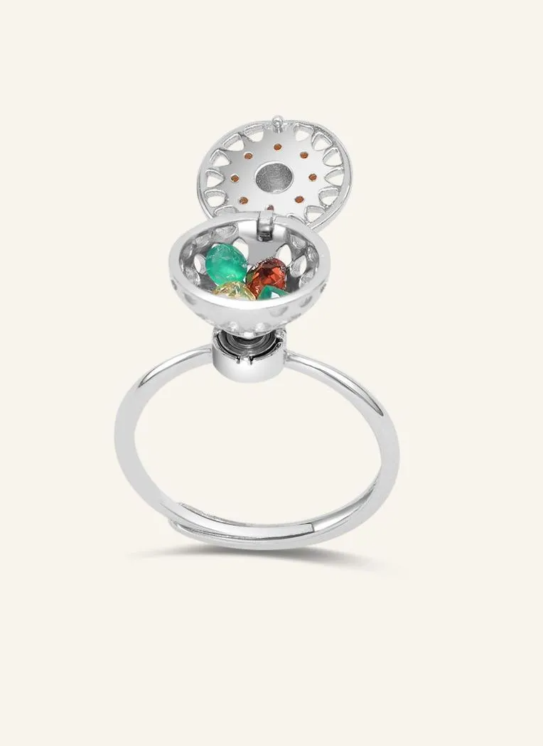 A silver ring with a rotating circular top that opens to reveal colorful gemstones inside, resembling a spinning hotpot.