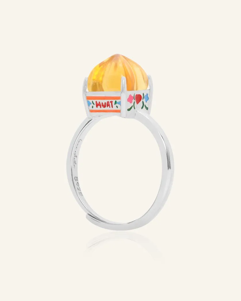 Silver Huat Kueh-inspired ring featuring a vibrant citrine gemstone as the steamed cake centerpiece, adorned with intricate enamel details, including 'Huat' and floral accents symbolizing prosperity and joy.