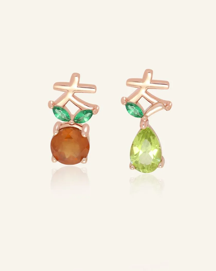 Rose gold lucky blessings ear studs featuring asymmetrical designs: one with a round orange Orange Garnet and the other with a pear-shaped Peridot, both accented with green marquise-shaped leaves and a stylized Chinese character symbol for blessings, representing prosperity and good fortune.