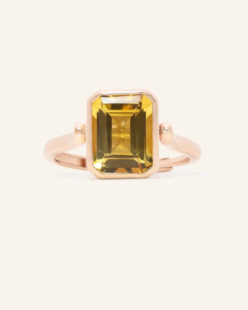 A rose gold ring featuring a reversible rectangular citrine gemstone adorned with intricate carvings and surrounded by cubic zirconias.