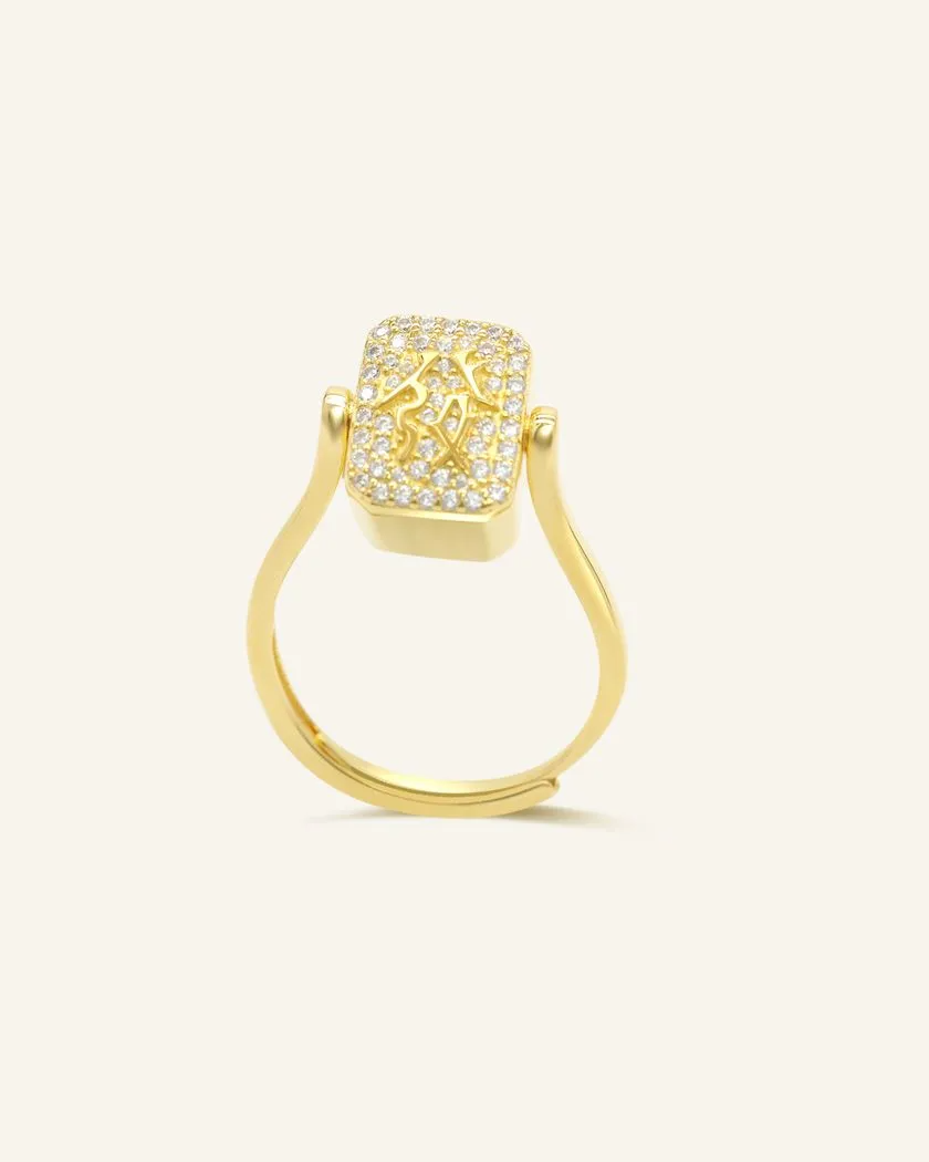 A yellow gold ring featuring a reversible rectangular citrine gemstone adorned with intricate carvings and surrounded by cubic zirconias.