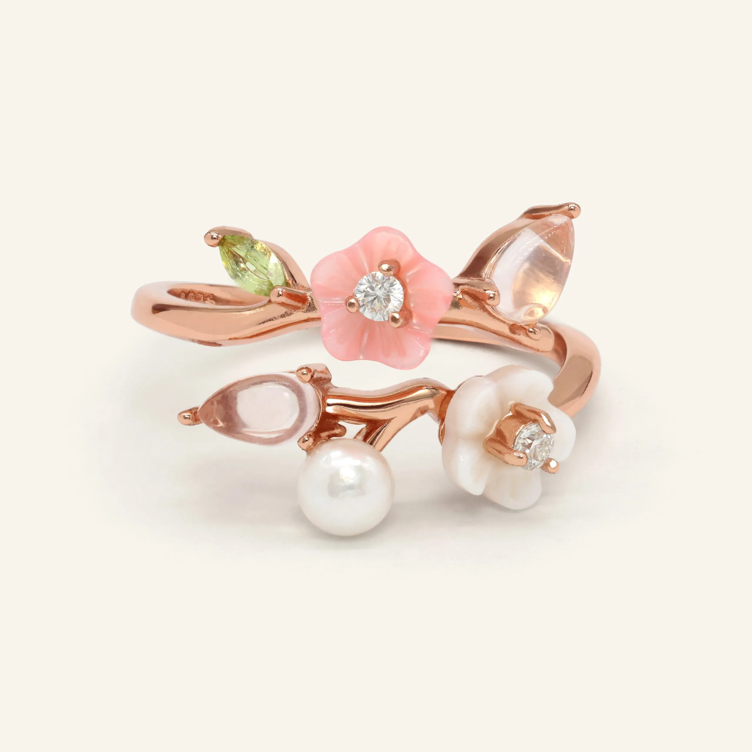 A rose gold Sakura Symphony Ring adorned with peridot, freshwater pearl, rose quartz, hand-carved shell flowers, and sparkling moissanite accents, capturing the essence of spring blossoms.