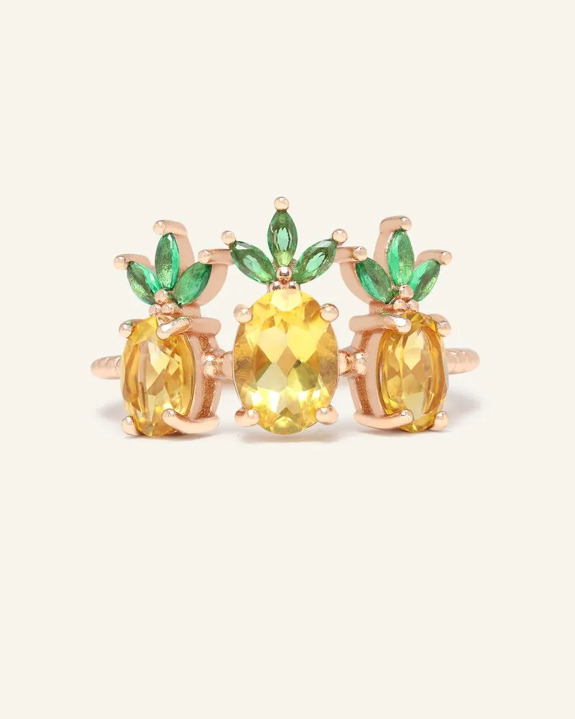 A trio of pineapple-themed rings featuring yellow citrine gemstones mimicking the fruit's body, with green cubic zirconia leaves at the top, all set in a rose gold band.